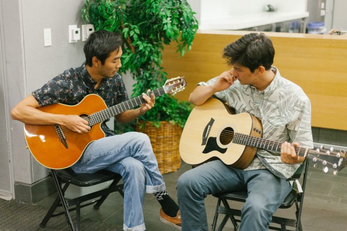Two men play the guitar.