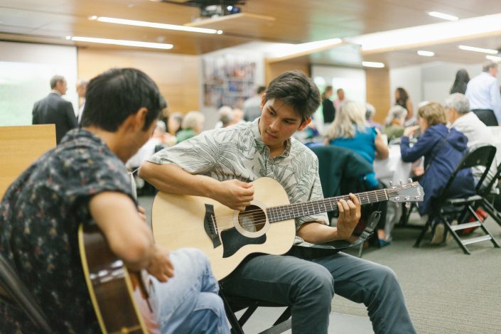 Two men play the guitar.