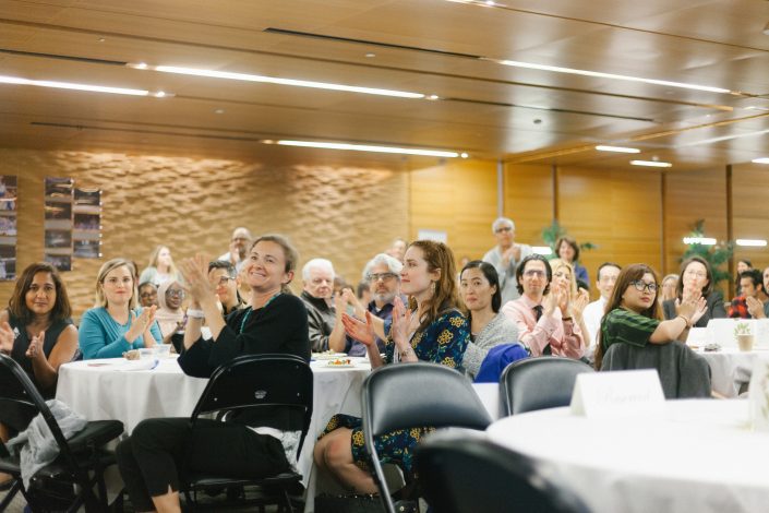 Guests sit around tables and clap.