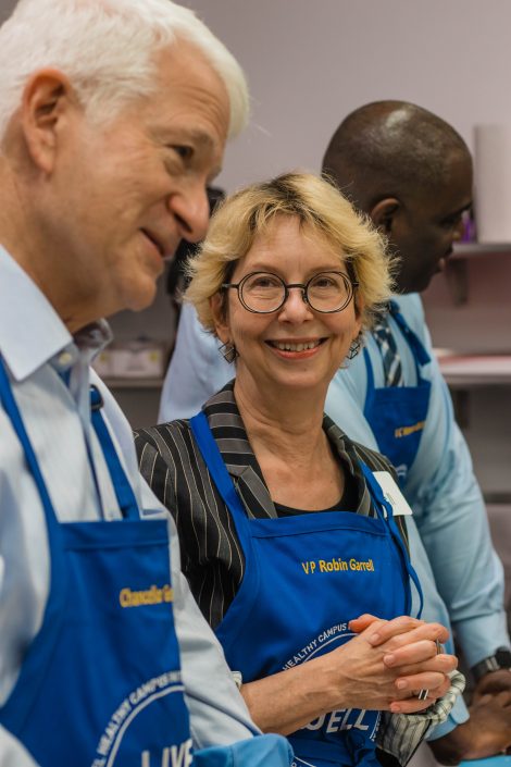 Woman in apron smiles at man in apron.