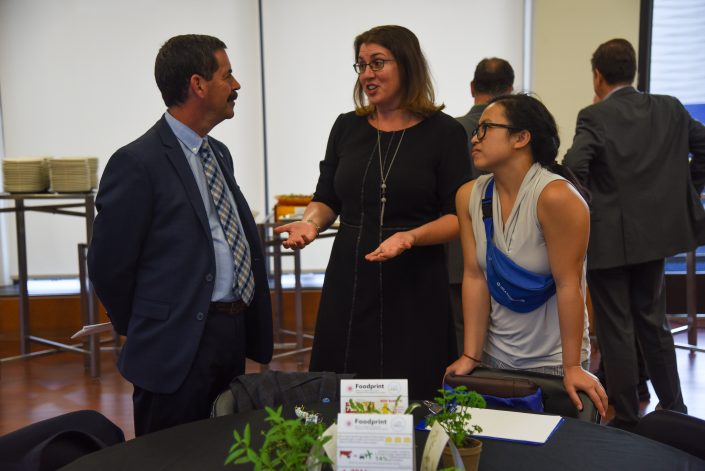 Man in suit and two women talk.