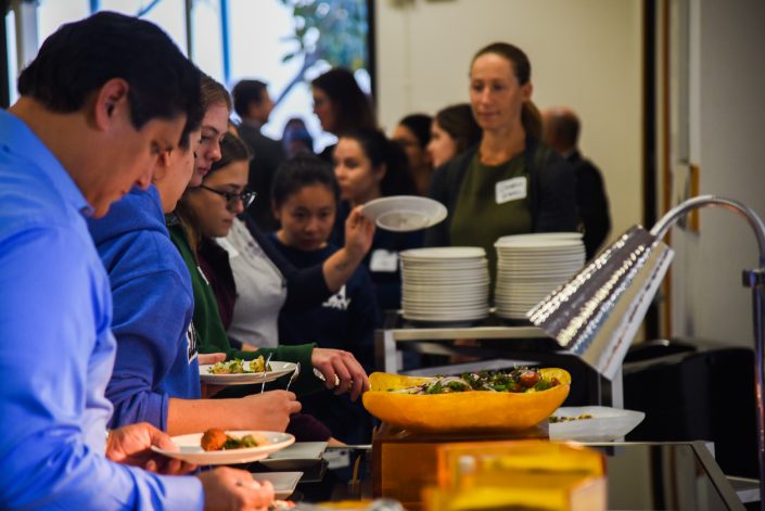 People serve themselves at a buffet style meal.